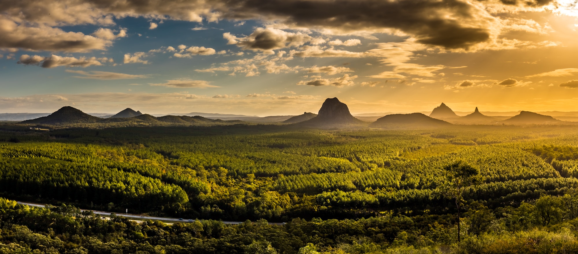Panoramic view of Glass House Mountains at sunset visible from W